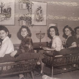 Four white women sitting at a table with a menorah