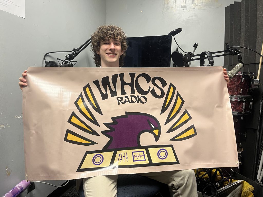 Horn holding a WHCS banner in the radio studio.