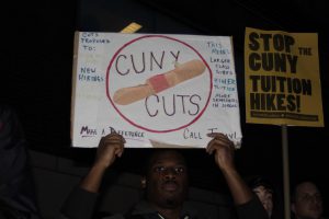 Man holding a sign protesting CUNY cuts.