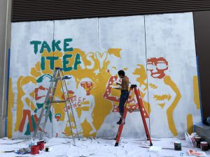 Women on latter painting a mural