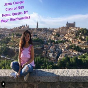 student sitting on a ledge behind an scenic view. 