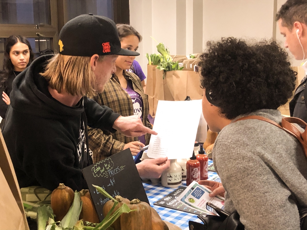 A GrowNYC representative shows a student a schedule for the Fresh Food Box