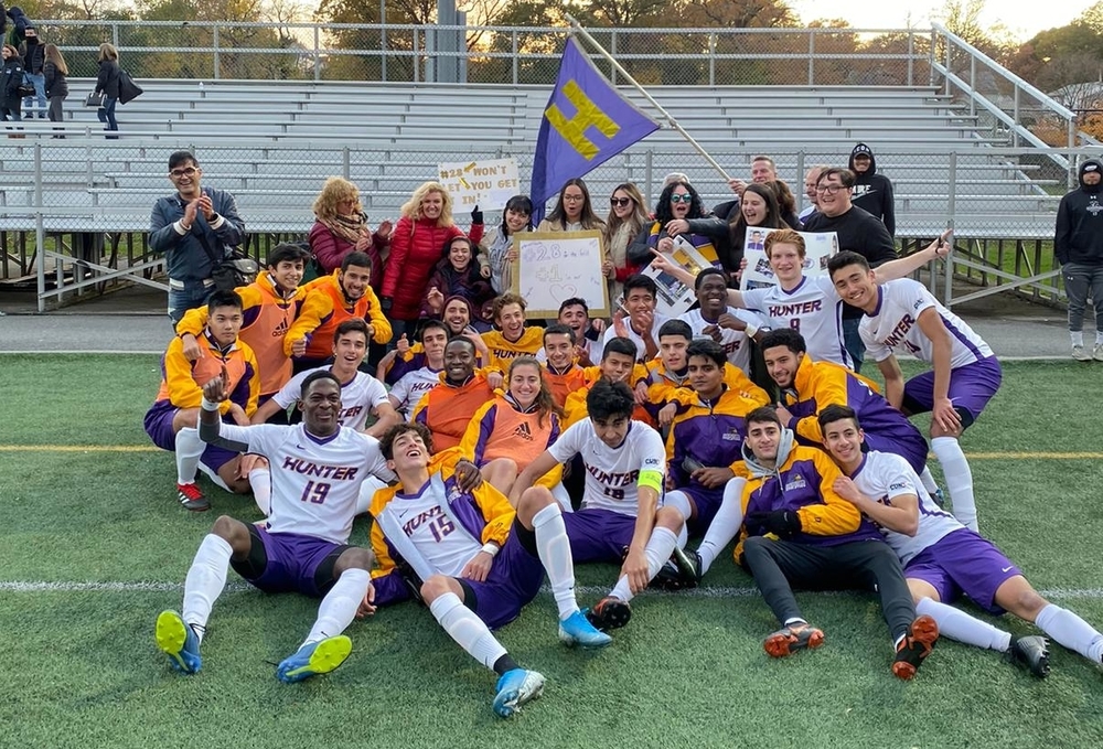 A group photo of the Hunter College men's soccer team, along with coaches and family members. Abirizk sits in the middle front.