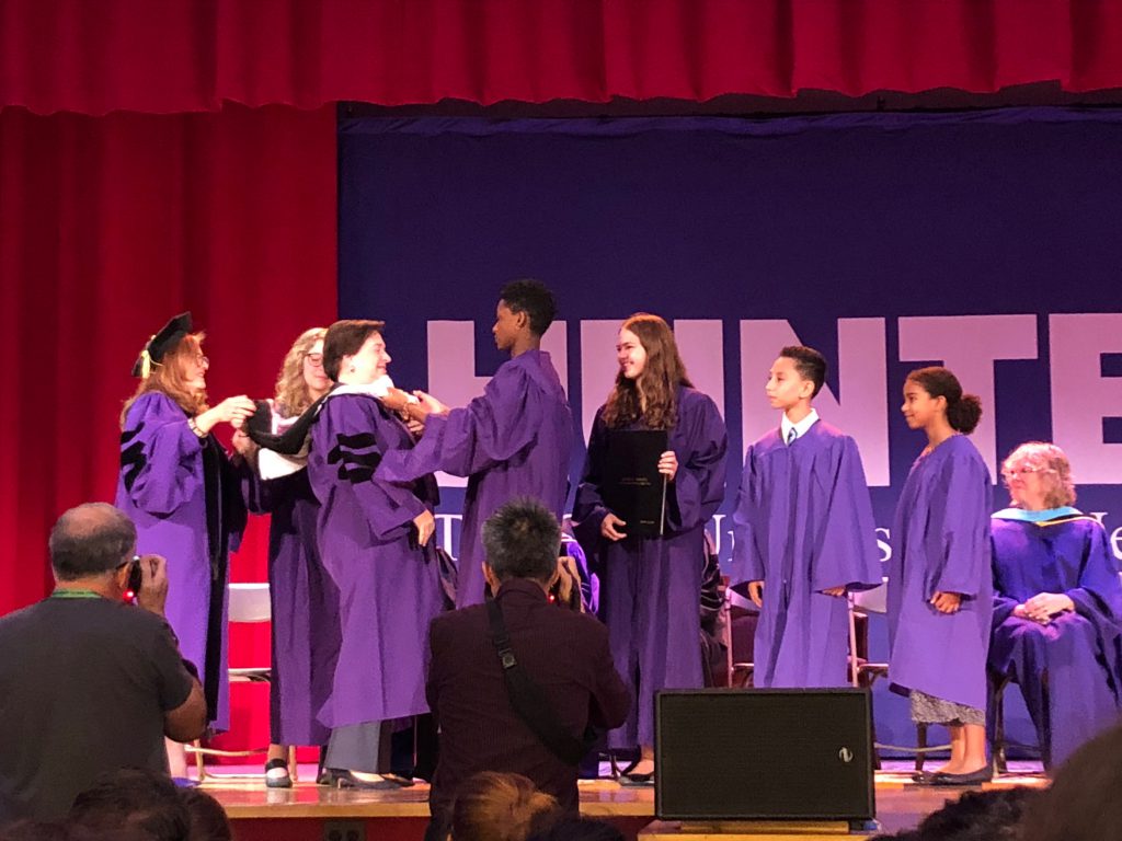 Demi Moore, a senior at Hunter College, places a hood around Kagan during the ceremony.